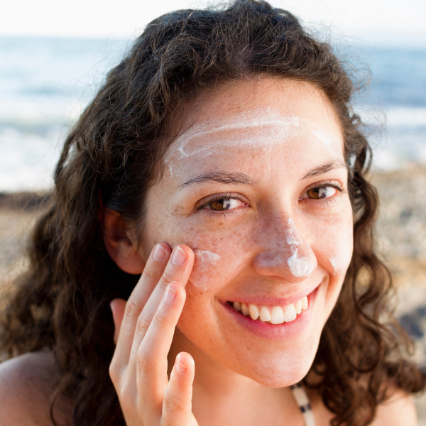 smiling-woman-applying-sunscreen-to-face-2022-03-07-23-55-53-utc